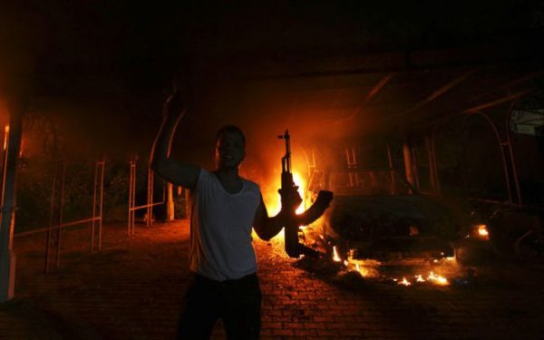 A protester reacts as the U.S. Consulate in Benghazi is seen in flames during a protest by an armed group said to have been protesting a film being produced in the United States September 11, 2012. An American staff member of the U.S. consulate in the eastern Libyan city of Benghazi has died following fierce clashes at the compound, Libyan security sources said on Wednesday. Armed gunmen attacked the compound on Tuesday evening, clashing with Libyan security forces before the latter withdrew as they came under heavy fire. REUTERS/Esam Al-Fetori